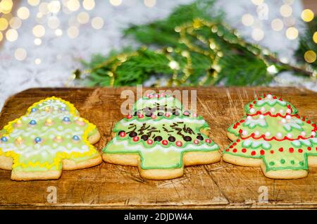Christmas gingerbread in the shape of Christmas trees lying on an old cutting Board. Baking for winter holidays Stock Photo
