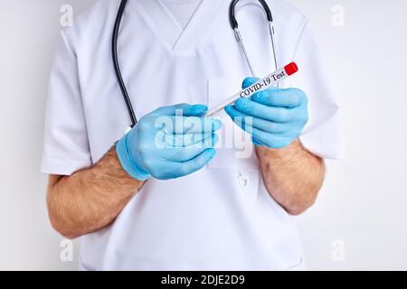 doctor scientist male holds sample tube in hand, examine it. doctor in biohazard protection clothing. covid 19 research laboratory. focus on tube Stock Photo