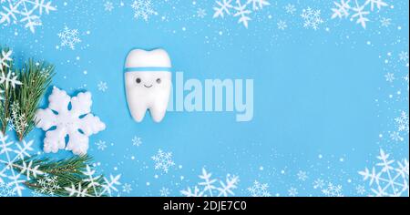 Baner for dentistry for Christmas and New Year with a tooth model on a blue background with a Christmas decor from snowflakes with copy space. Stock Photo