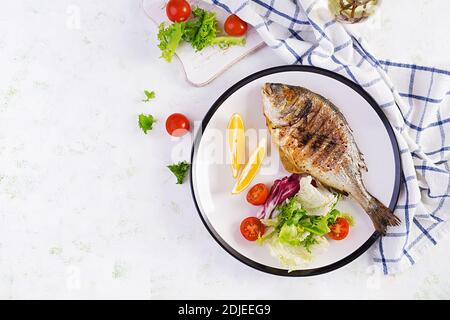 Delicious grilled dorado or sea bream fish with salad, spices, grilled dorada on a plate. Top view, overhead, copy space Stock Photo