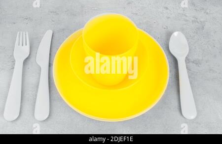 picnic illuminating yellow cutlery utensils, plates, cups, fork, spoon and knife on trendy ultimate grey background. Eco friendly, plastic garbage for Stock Photo
