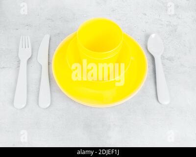 picnic illuminating yellow cutlery utensils, plates, cups, fork, spoon and knife on trendy ultimate grey background. Eco friendly, plastic garbage for Stock Photo