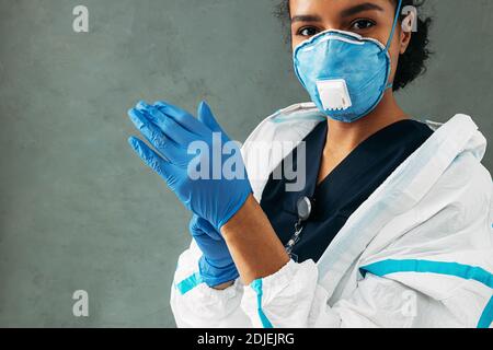 Young medical worker puts on surgical gloves looking at camera Stock Photo