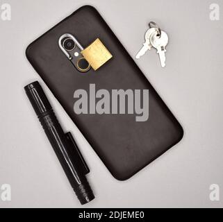 Mobile phone with padlock on the camera, keys and pen. Stock Photo