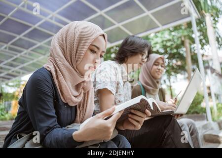 Portrait Muslim female student reading a book. With his friends in the background Stock Photo