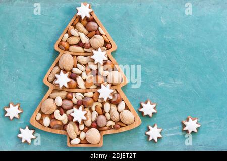Nuts and cookies in Christmas tree-shaped bowl on blue background Stock Photo