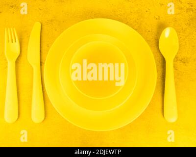 picnic yellow cutlery utensils, plates, cups, fork, spoon and knife on illuminating background Stock Photo