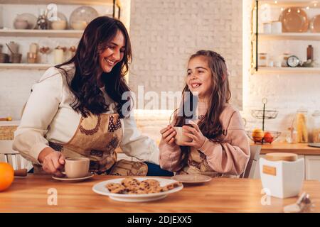 Family drinking tea with Christmas cookies on kitchen at home after cooking biscuits. Mother and daughter having fun Stock Photo