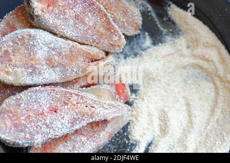 Cooking fish dishes. Raw pieces of pink salmon or chum salmon in breadcrumbs are on the plate.  Stock Photo