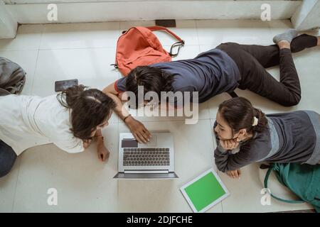 Portrait fun students lying down working in groups on the floor Stock Photo