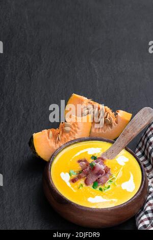 Autumn  pumpkin cream soup with bacon on black stone backgound Stock Photo