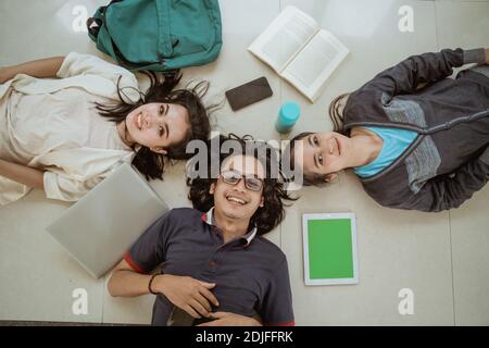 Portrait fun students lying down working in groups on the floor Stock Photo