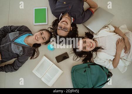 Portrait fun students lying down working in groups on the floor Stock Photo