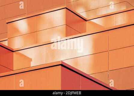 Orange colored geometric background of metal building facade. Abstract architectural shapes and lines Stock Photo