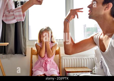 daughter is tired of family conflicts,divorce and children concept. little kid girl sit upset with quarrelling of parents, they are going to be divorc Stock Photo