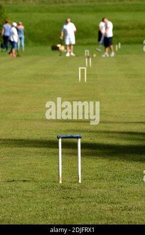 Metal hoop on a croquet lawn, with players blurred in the background Stock Photo