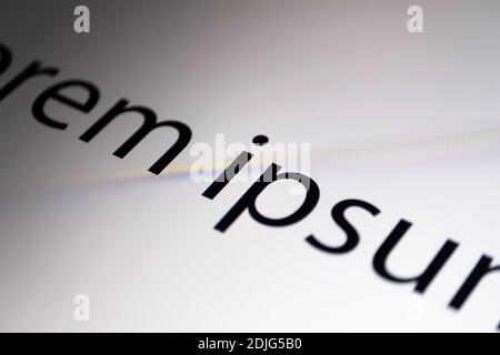 Close-up of part of black and white Lorem Ipsum text diagonally across a monitor screen with focus on the letter i in the middle Stock Photo