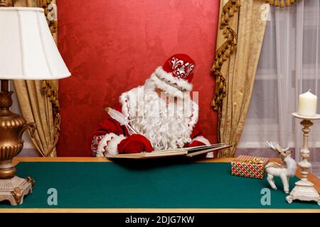 Santa Claus write on the  book sitting at the table. Copyspace. Stock Photo