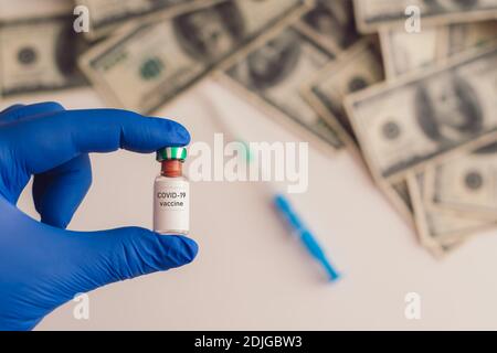 covid-19 vaccine in hand with money in the background Stock Photo