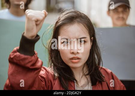 Portrait female students demonstrating with their friends holding blank paper in the background Stock Photo