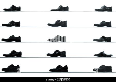 Men classic shoes displayed on shop shelves against back lit white background. High contrast black and white abstract looking picture Stock Photo