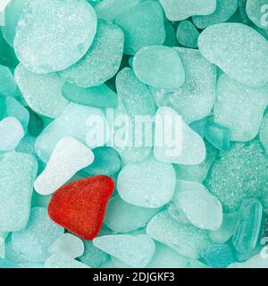 Unique red sea glass isolated on green sea glass background Stock Photo