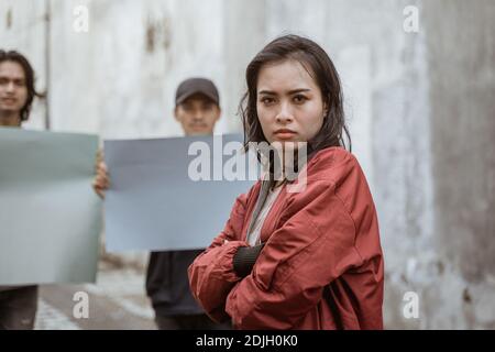 Portrait female students crossing their arms demonstrating with their friends holding blank paper Stock Photo