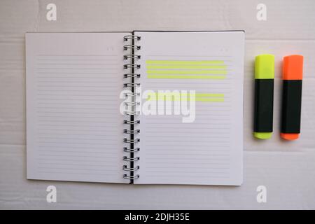 orange and yellow hihglighter on the empty lined notebook. preparation of make a homework.Business work area concept. Stock Photo