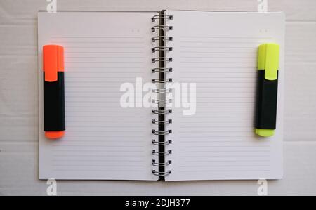 orange and yellow hihglighter on the empty lined notebook. preparation of make a homework.Business work area concept. Stock Photo