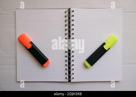 orange and yellow hihglighter on the empty lined notebook. preparation of make a homework.Business work area concept. Stock Photo
