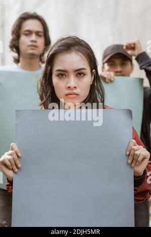 Portrait female students demonstrating with their friends holding blank paper Stock Photo