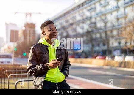Young man using smart phone outdoors at urban setting Stock Photo