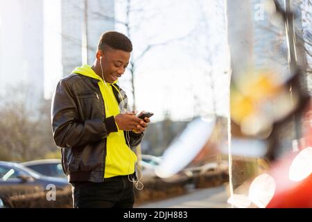 Young man using smart phone outdoors at urban setting Stock Photo