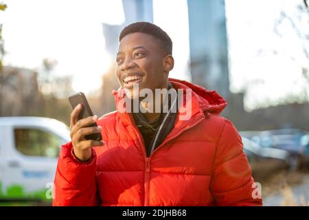 Young man using smart phone outdoors at urban setting Stock Photo