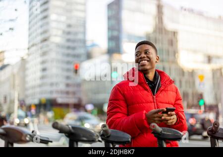 Young man using smart phone outdoors at urban setting Stock Photo