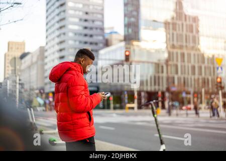 Young man using smart phone outdoors at urban setting Stock Photo