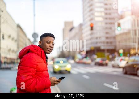 Young man using smart phone outdoors at urban setting Stock Photo