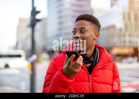 Young man using smart phone outdoors at urban setting Stock Photo