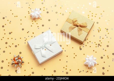 Two gifts in boxes on yellow backgound with baubles and confetti. Christmas, New Year concept. Top view, flat lay. Stock Photo