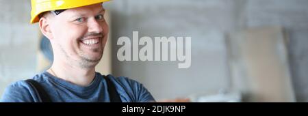 Cheerful male worker in yellow helmet holding brick Stock Photo