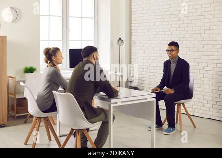 Two HR managers talking to young African-American candidate during job interview Stock Photo