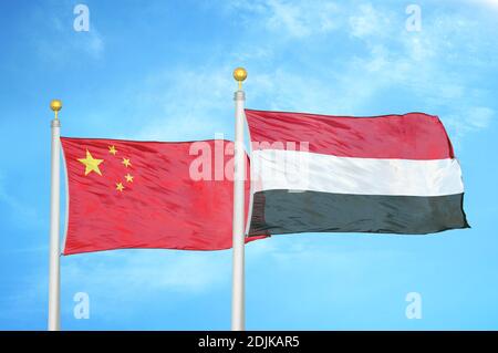 China and Yemen two flags on flagpoles and blue cloudy sky Stock Photo