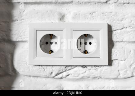 Plastic German double socket-outlets type F with grounding. Pair of empty, unplugged, european white power sockets or electrical outlets CEE 7 with Stock Photo