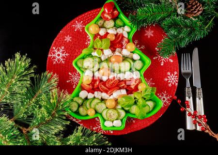 Christmas tree salad made from sliced fresh cucumber, tomato and mozzarella cheese. New Year or Christmas dinner. Stock Photo