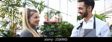 Cheerful man giving flower to charming lady in plant store Stock Photo