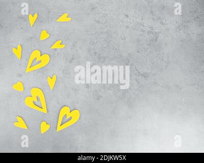 decorative yellow wooden heart shapes on grey concrete surface. Demonstrating trendy colors of year 2021. Greeting card for Valentine's Day. Flatlay. Stock Photo