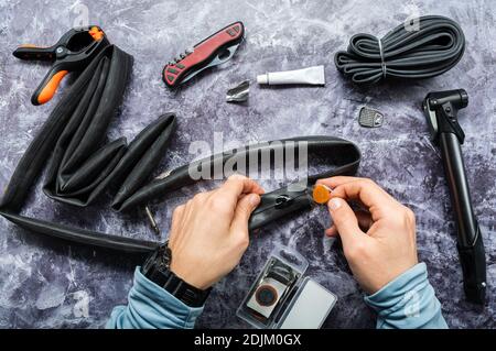 A patch with glue in the hands of the master. The master applies a patch to the hole. Top. Stock Photo