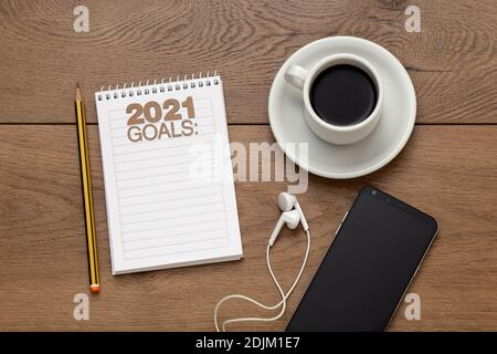 2021 Goals blank notebook pencil and cup of coffee . Business concept of top view goals list over wooden desk. Stock Photo