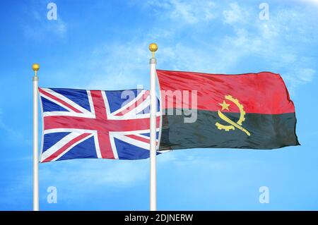 United Kingdom and Angola two flags on flagpoles and blue cloudy sky Stock Photo