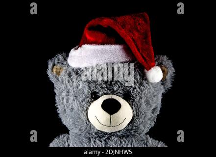Toy teddy bear with Christmas santa hat isolated on a black background Stock Photo